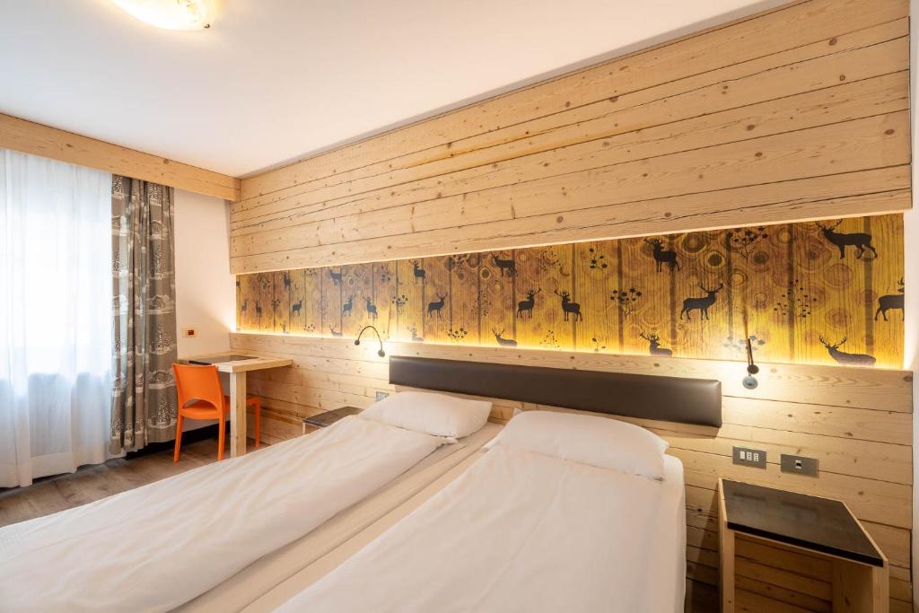 een slaapkamer met een bed en een houten muur bij Hotel Italia in Canazei