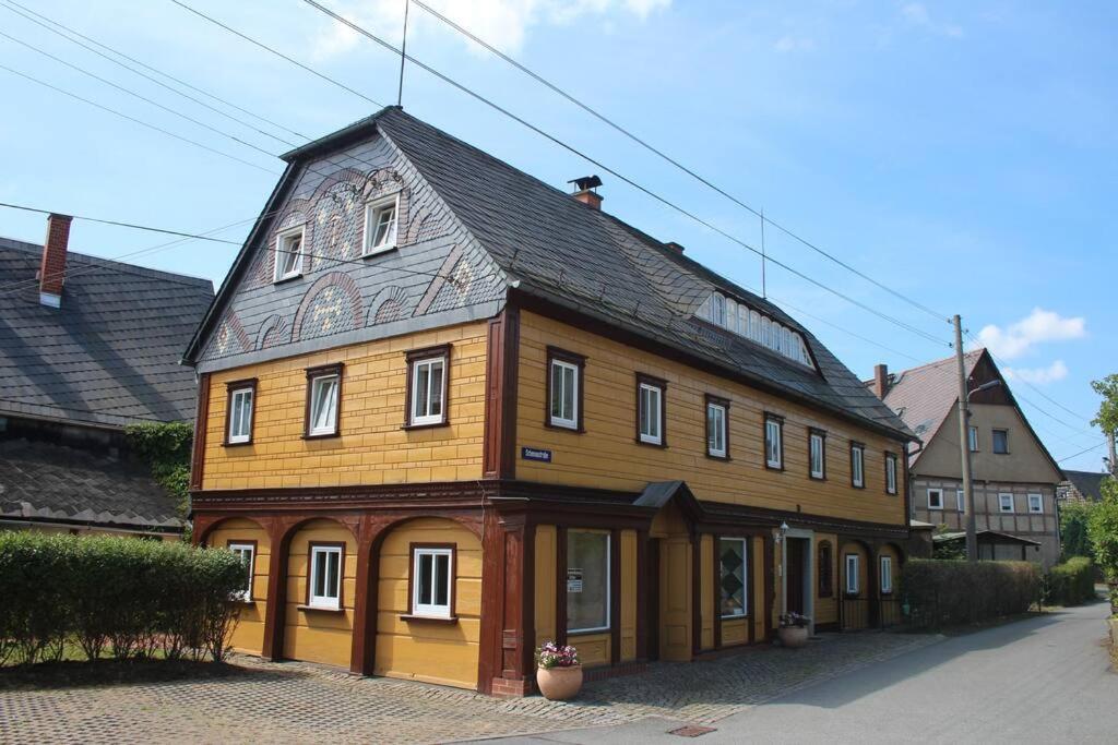 a large wooden house with a black roof at Maisonette-FeWo Fritz mit Infrarotsauna in Großschönau