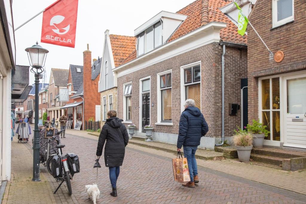 two women walking down a street with a dog at B & B TX71 in Den Burg