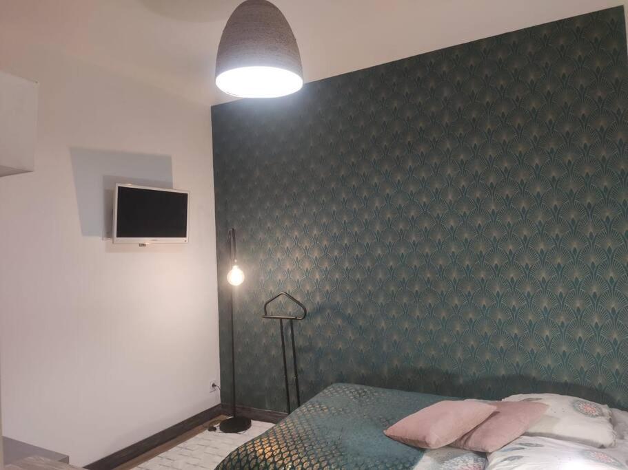 um quarto com uma parede verde com uma cama e um candeeiro em Studio Le pigeonnier em Tallard