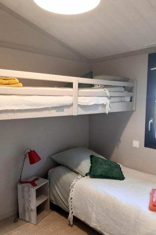 a bedroom with two bunk beds and a lamp at Chalet la lande in Ondres