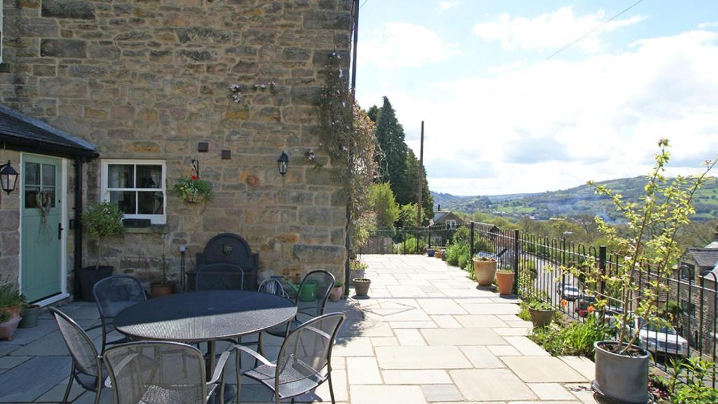 a patio with a table and chairs and a building at Springbank in Two Dales