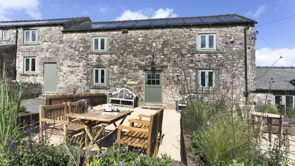 a stone cottage with a table and chairs in front of it at Golconda Cottage in Brassington