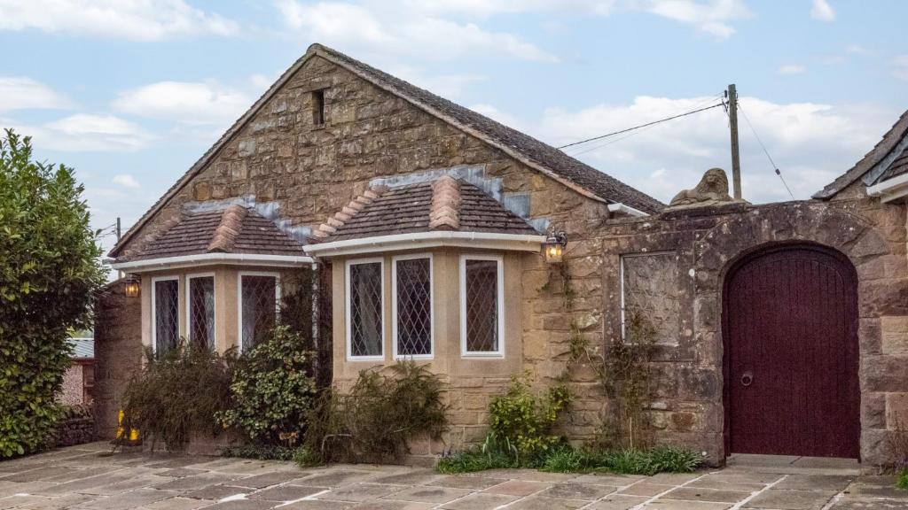 an old stone house with a red door at Stanton Lodge Cottage in Curbar