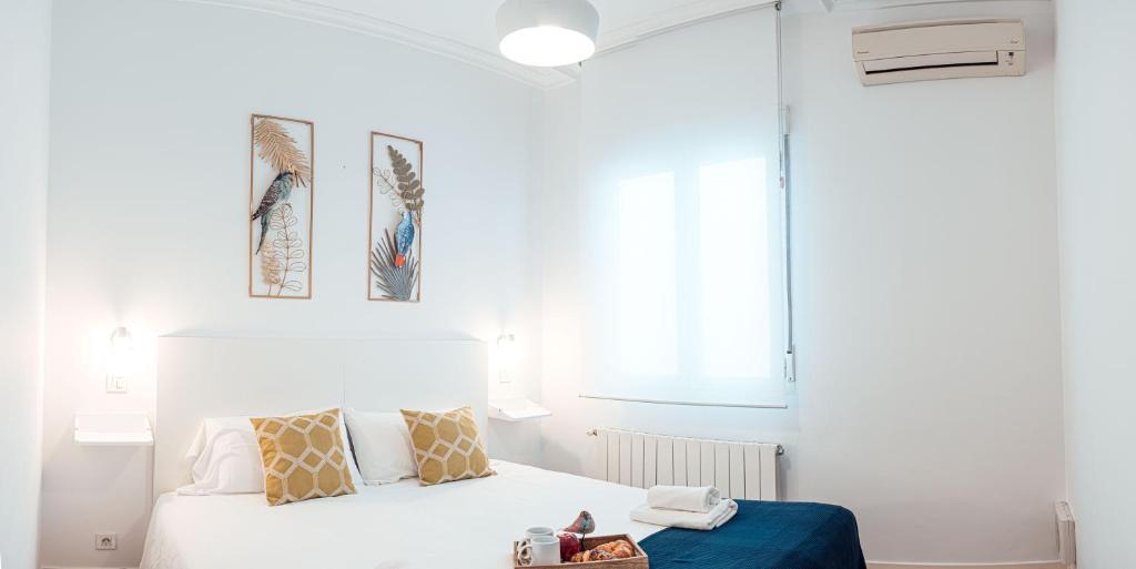 a white bedroom with a bed and two pictures on the wall at My City Home - Amplio apartamento en Salamanca in Madrid