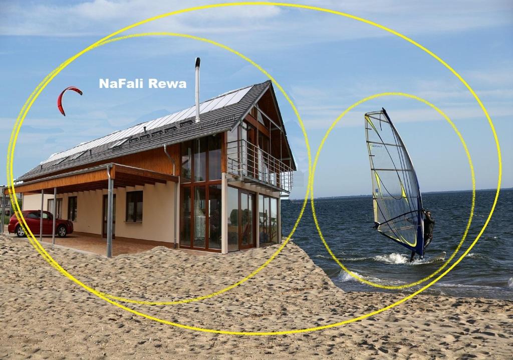 una casa en la playa con un windsurf delante en Gdynia noclegi NaFali Rewa en Rewa