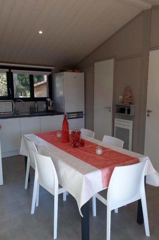 a white table with white chairs and a kitchen at Chalet la lande in Ondres
