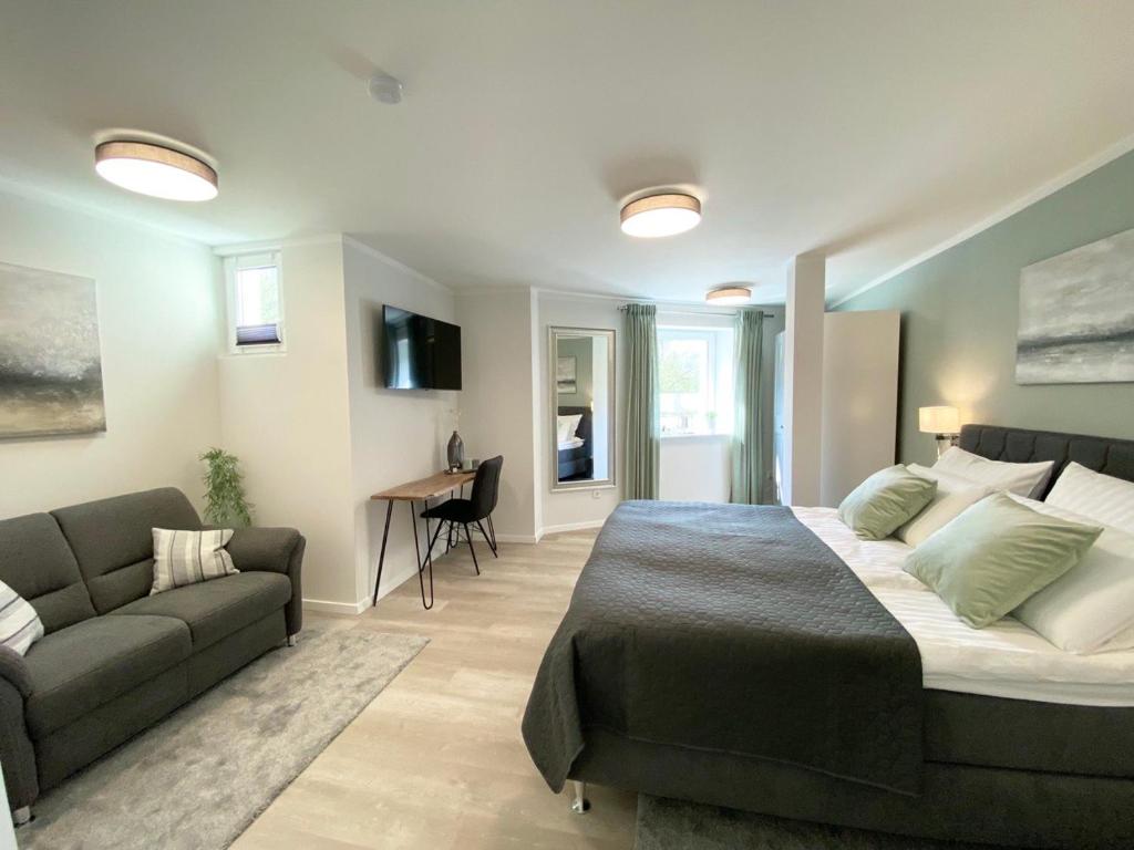 - une chambre avec un grand lit et un canapé dans l'établissement QT Apartments Detmold, à Detmold