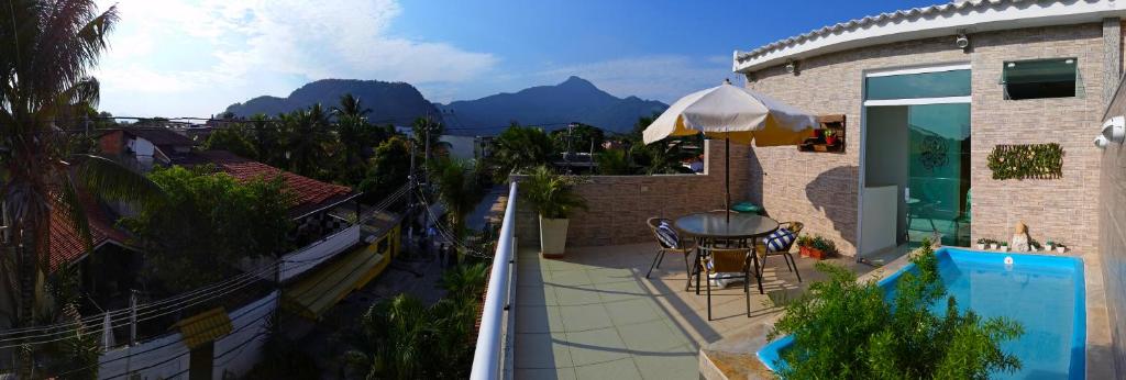 un balcone di una casa con tavolo e ombrellone di Pousada da Gigoia - Barra da Tijuca a Rio de Janeiro