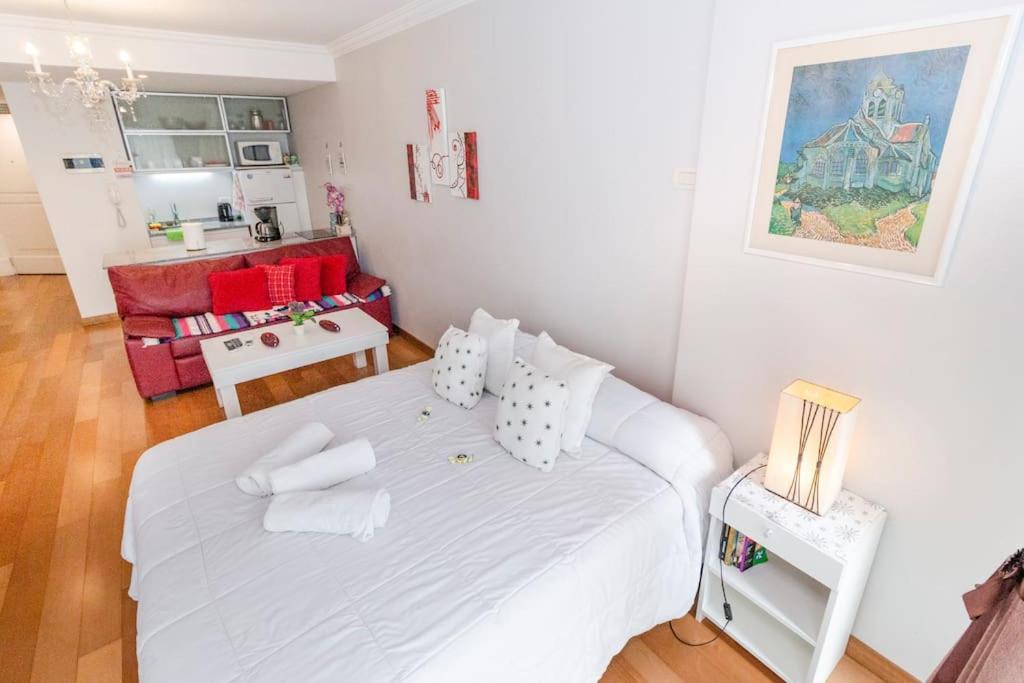 a bedroom with a white bed and a living room at Departamento en Peña Recoleta MODERNO Y LUMINOSO in Buenos Aires