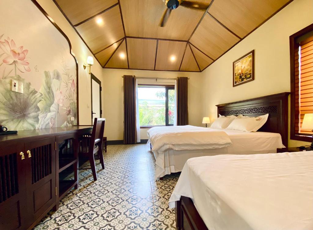 a hotel room with two beds and a window at Le Jardin De Tam Coc in Ninh Binh