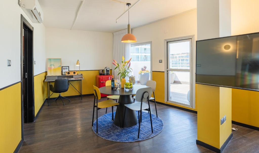a dining room with yellow walls and a table and chairs at PLAY Seaport Suite Hotel TLV in Tel Aviv