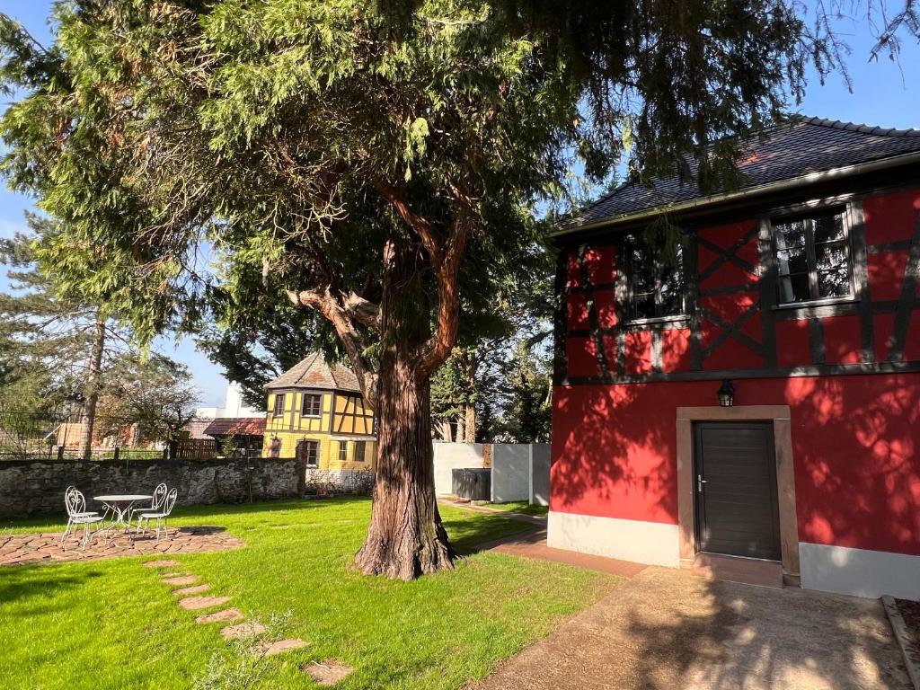 a red building with a tree in the yard at Le Parc du Séquoia & SPA proche Colmar et Riquewihr in Ostheim