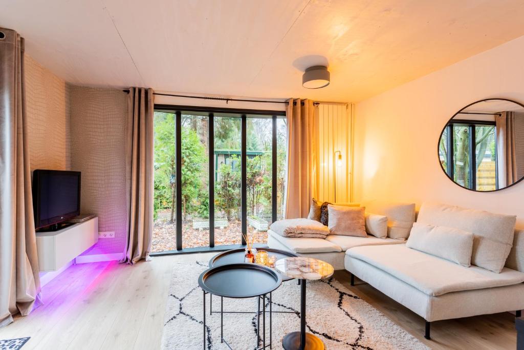 een woonkamer met een bank en een tv bij Boutique Chalet Veluwe in Putten