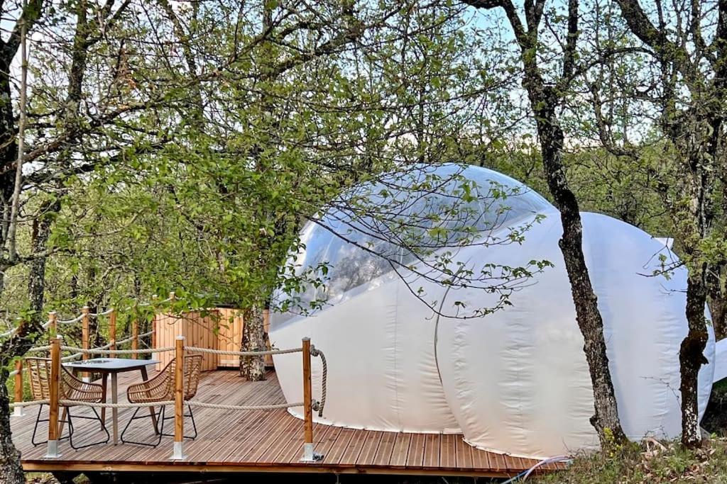 une tente sur une terrasse en bois dans les bois dans l'établissement Fun'ambulle, à Féneyrols
