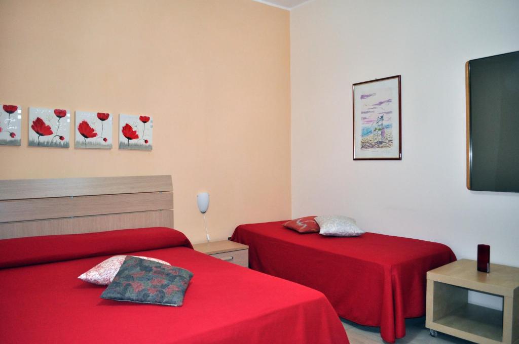 Montalbano JonicoにあるB&B Le Zagareの赤いシーツが備わるドミトリールームのベッド2台