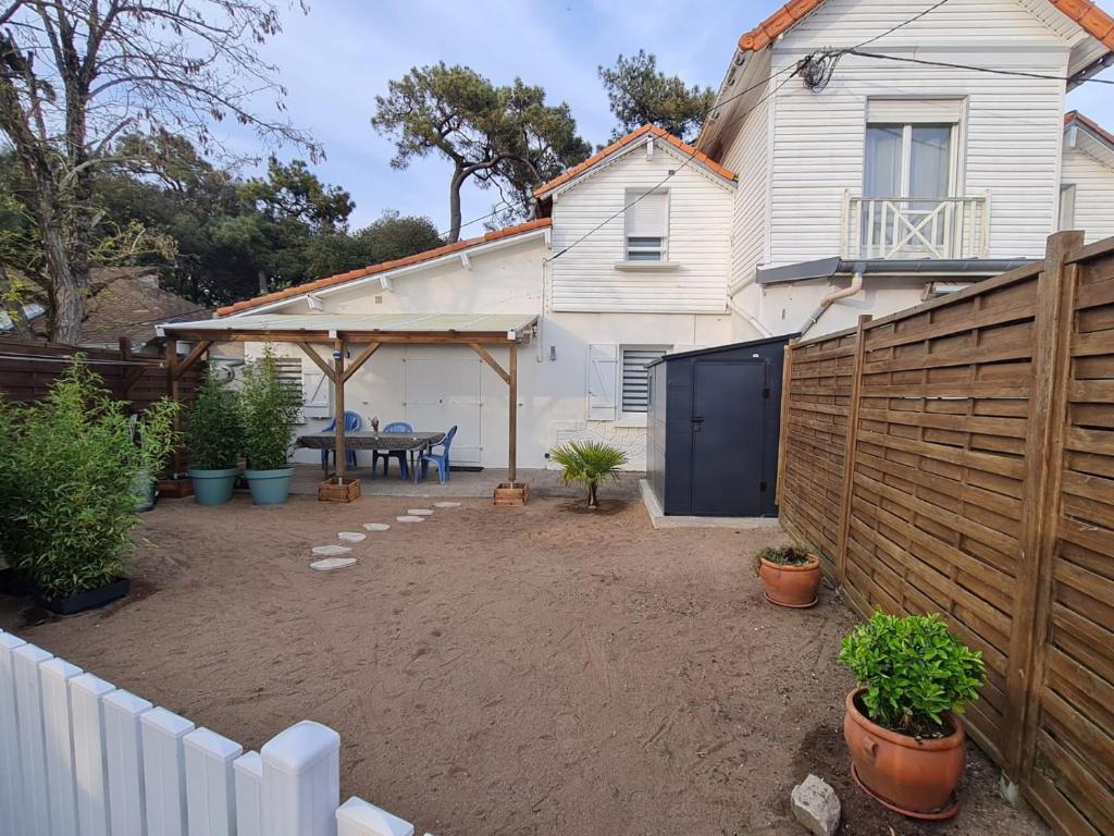 un patio trasero con una valla y una casa blanca en Maison location Saint Brévin l'Océan, en Saint-Brevin-les-Pins