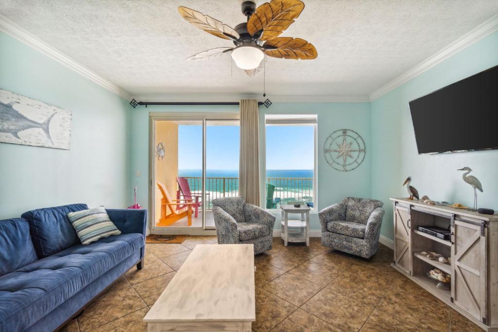 un salon avec un canapé bleu, des fauteuils et une télévision dans l'établissement Treasure Island 1005, à Panama City Beach
