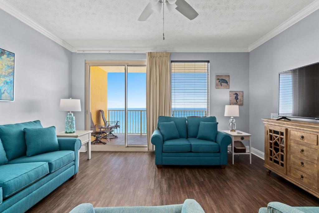 a living room with two blue chairs and a television at Treasure Island 2109 in Panama City Beach