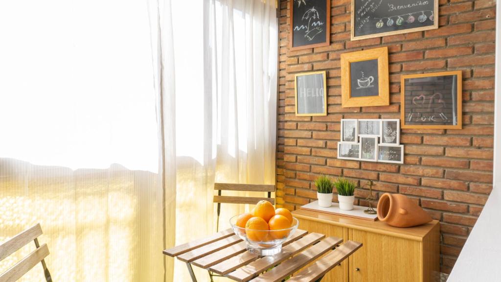 a room with a table with a bowl of oranges on it at Home Amatista Málaga in Málaga