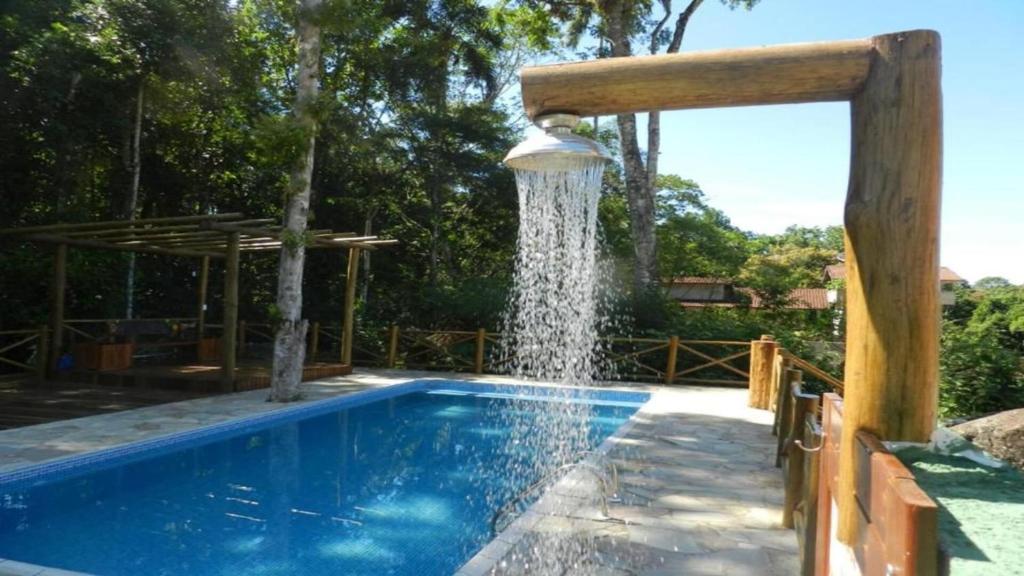 a swimming pool with a water fountain at Chalés Yababali in Ubatuba