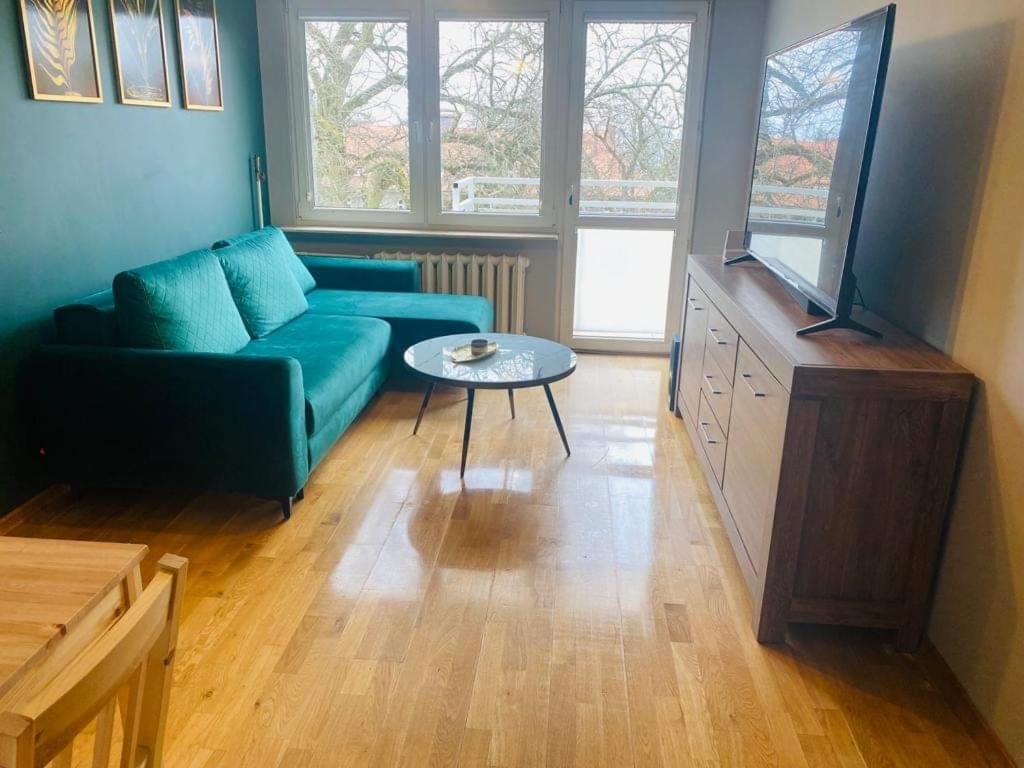 a living room with a blue couch and a table at Przestronny apartament in Giżycko