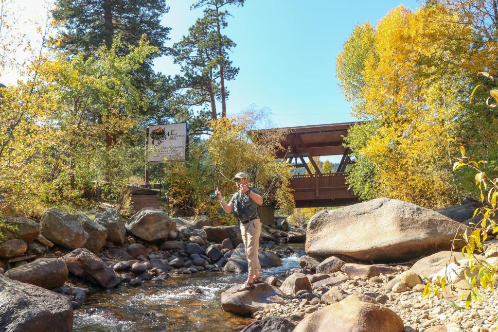 Ein Mann steht auf einem Felsen in einem Bach in der Unterkunft Castle Mountain Lodge in Estes Park