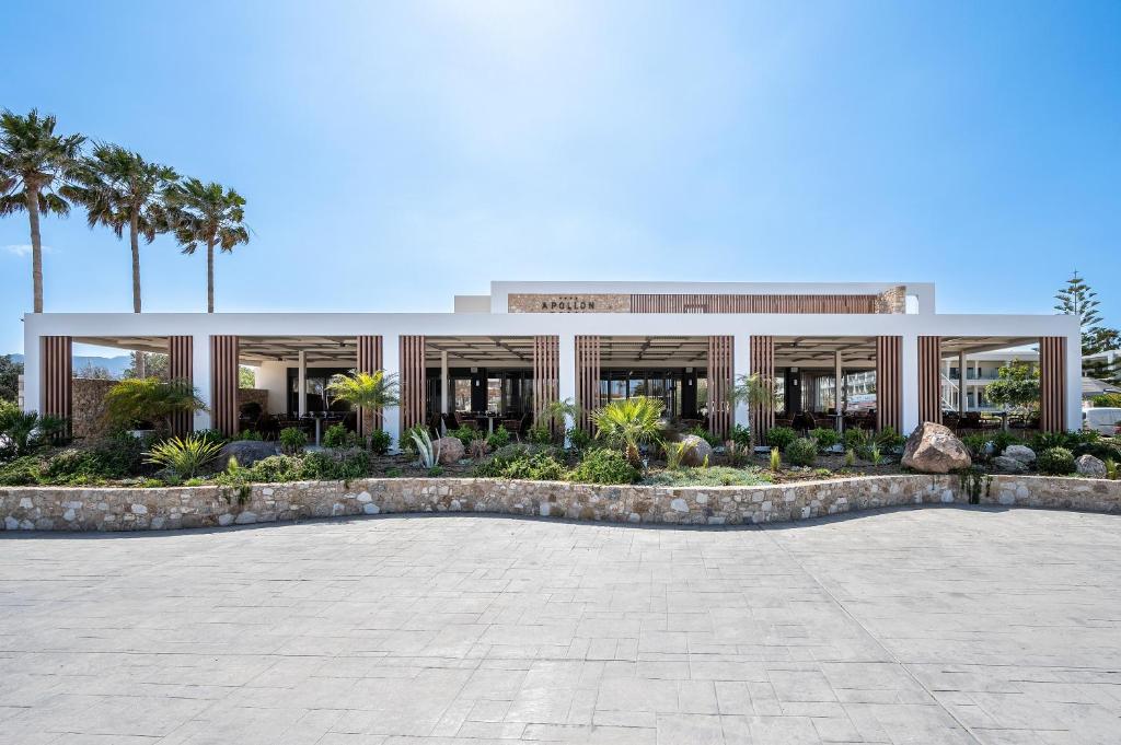 un bâtiment avec des palmiers en face de celui-ci dans l'établissement Apollon Hotel, à Kos