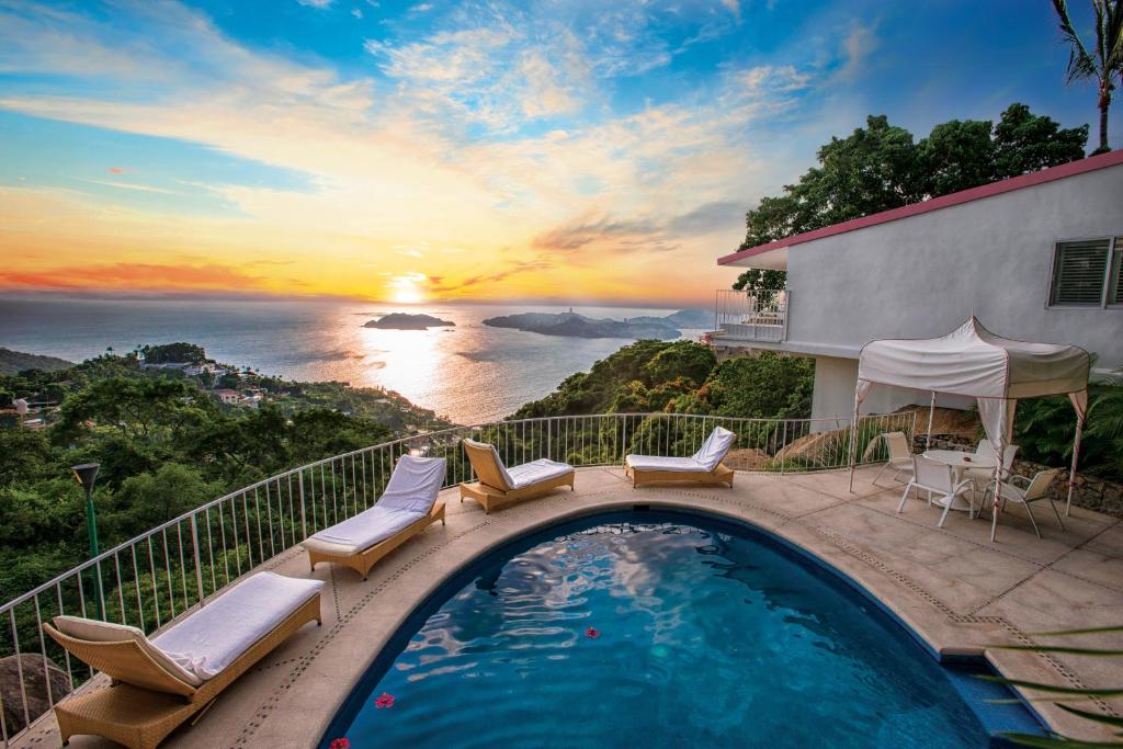 a swimming pool with chairs and a view of the ocean at Las Brisas Acapulco in Acapulco