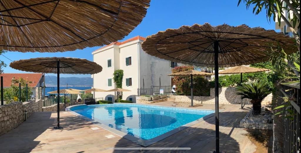 a swimming pool with two umbrellas in front of a building at Villa Salena with pool Slatine in Slatine