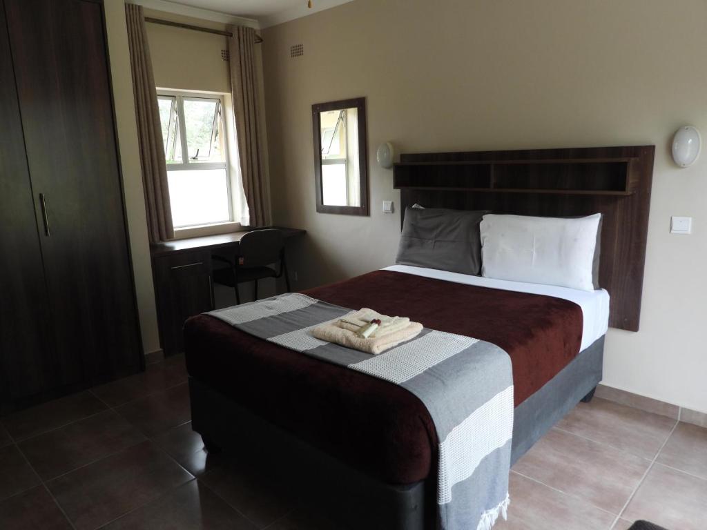 a bedroom with a large bed with two towels on it at 2 Bed Apt with en-suite and kitchenette - 2067 in Harare