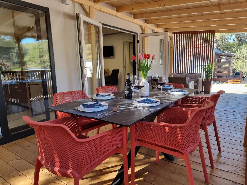 une table à manger avec des chaises rouges, une table et des chaises dans l'établissement Premium mobile home SUN & JOY - Oaza Mira Camping, à Drage