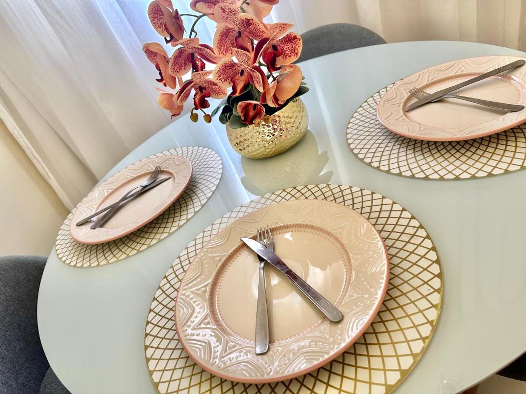 a white table with plates and utensils on it at Ap Penélope charmosa in Teresina