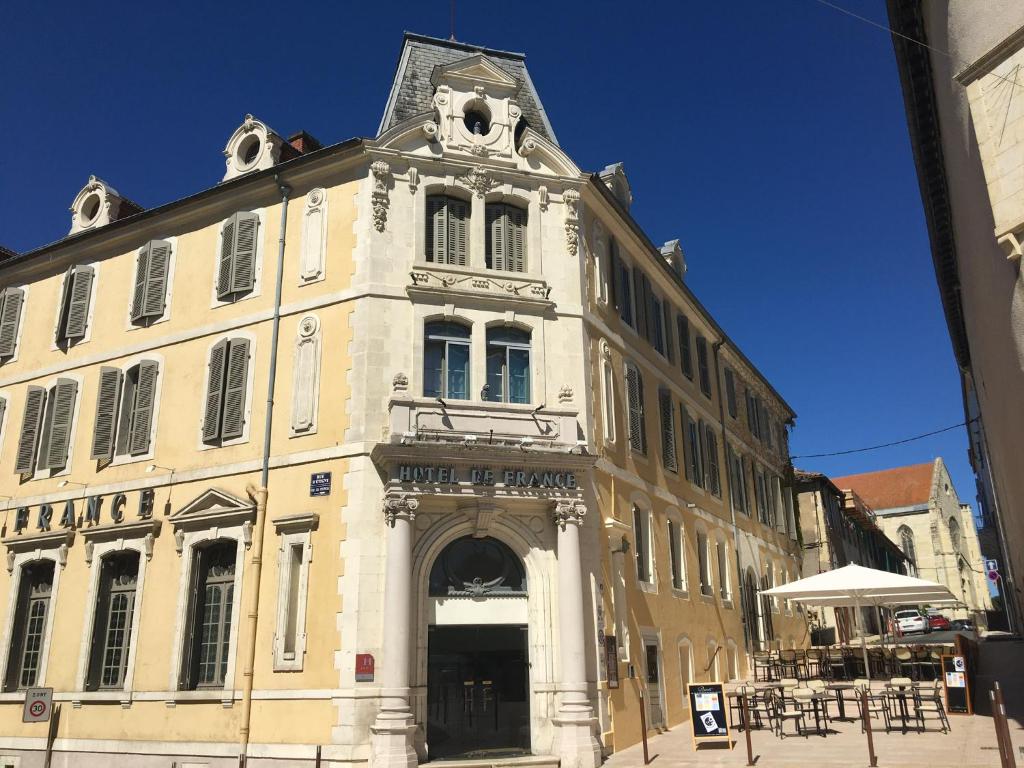 a large white building with an archway on a street at Hôtel de France in Auch