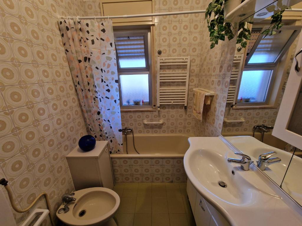 een badkamer met een wastafel, een toilet en een bad bij Mondello Sunrise in Mondello
