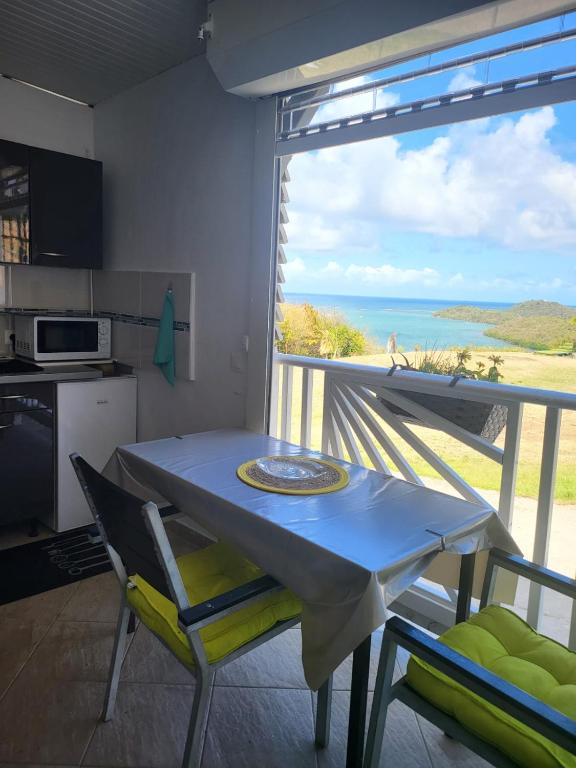 una mesa y sillas en una cocina con vistas al océano en Petit paradis location en Le Vauclin