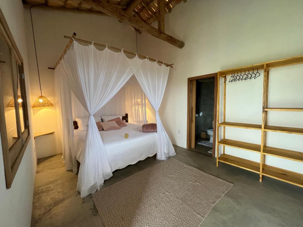 a bedroom with a white bed with a canopy at Villa Savoia Corumbau in Corumbau
