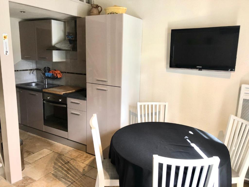 eine Küche mit einem Tisch und Stühlen sowie einem TV in der Unterkunft Havre de paix aux portes de la Provence Verte in Forcalqueiret