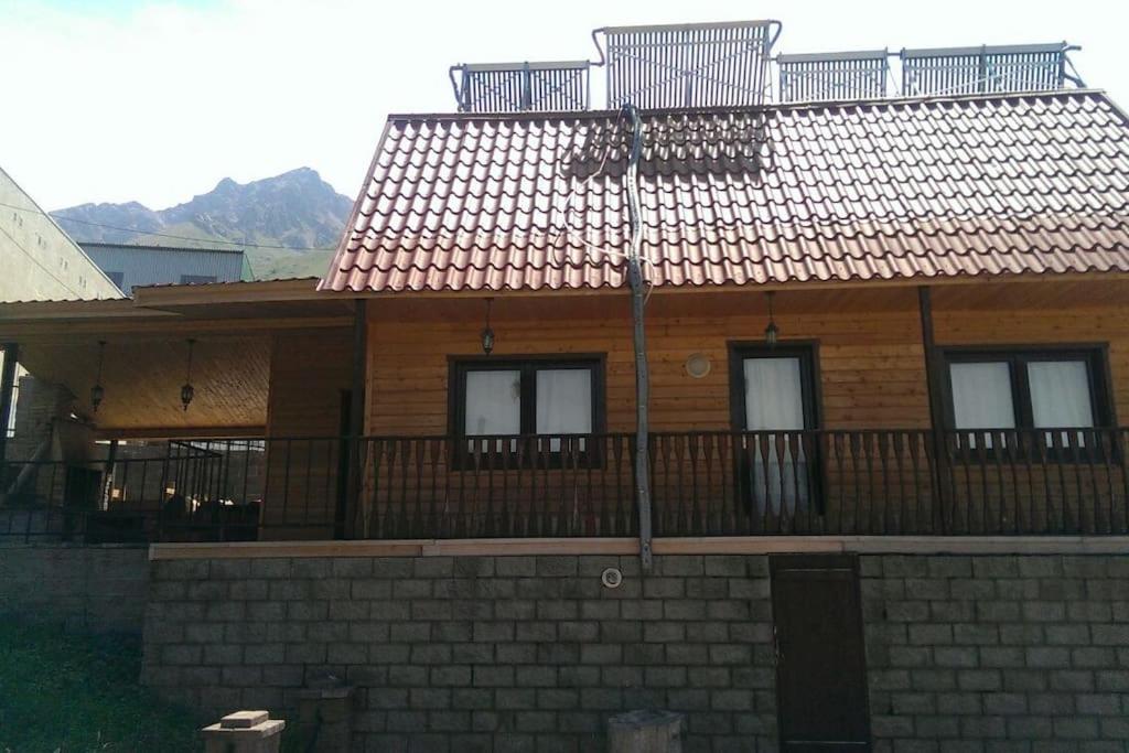 een houten huis met een balkon erboven bij WhiteForShymbulak in Besqaynar