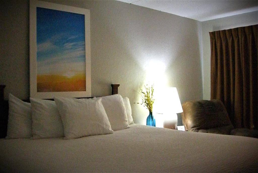 a bedroom with a bed with a lamp and a chair at Days Inn by Wyndham Pierre in Pierre