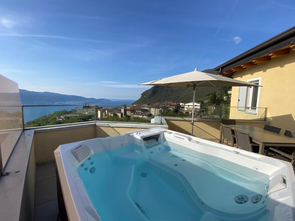 un bain à remous sur un balcon avec un parasol dans l'établissement Residence La Villa Tignale, à Tignale
