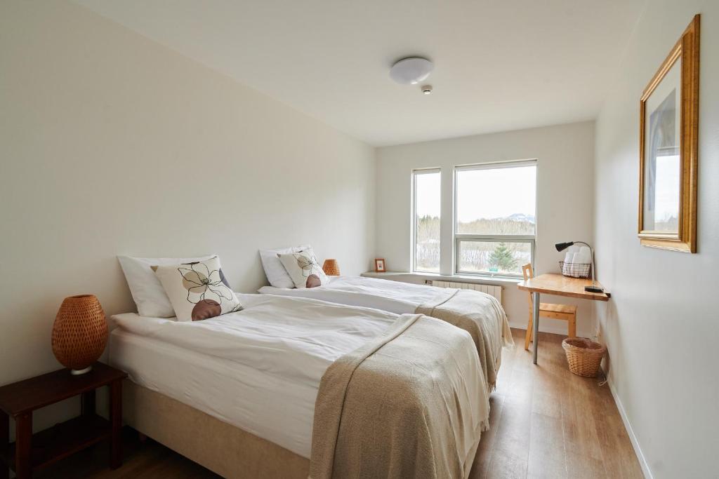a white bedroom with a large bed and a window at Solheimar Eco-Village Guesthouse in Sólheimar