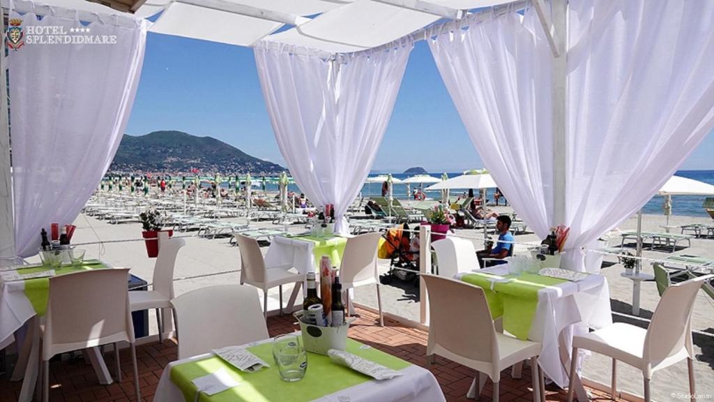 un grupo de mesas y sillas en la playa en Hotel Splendid Mare, en Laigueglia