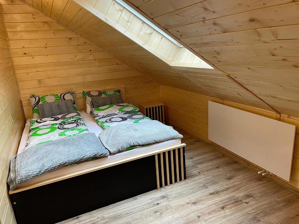 a small bed in a room with wooden walls at Apartament na poddaszu u Reni in Grywałd