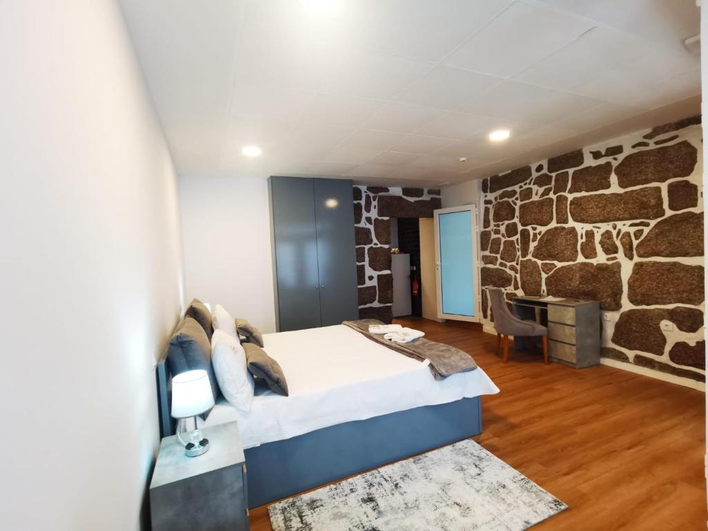 um quarto com uma cama e uma parede de pedra em Alojamento Local F&B em Guimarães