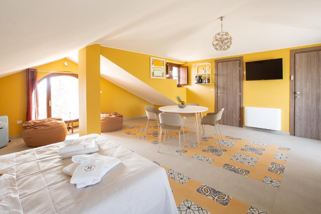 1 dormitorio con cama, mesa y paredes amarillas en Locanda Ballarò Relais di Campagna en Deliceto