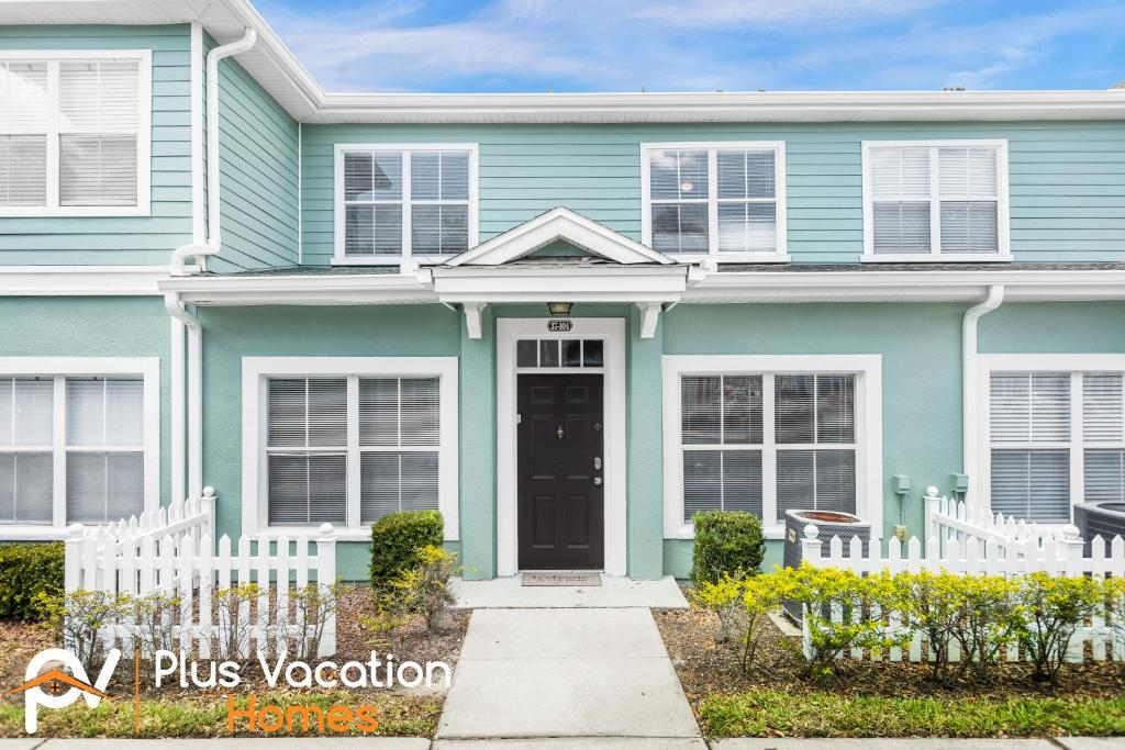 una casa azul con una valla blanca en 2222 Venettian Bay retreat- 3 bedroom full of amenities, en Kissimmee