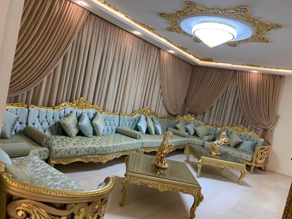a living room with a blue couch and golditures at Maison Fathallah in Mahdia