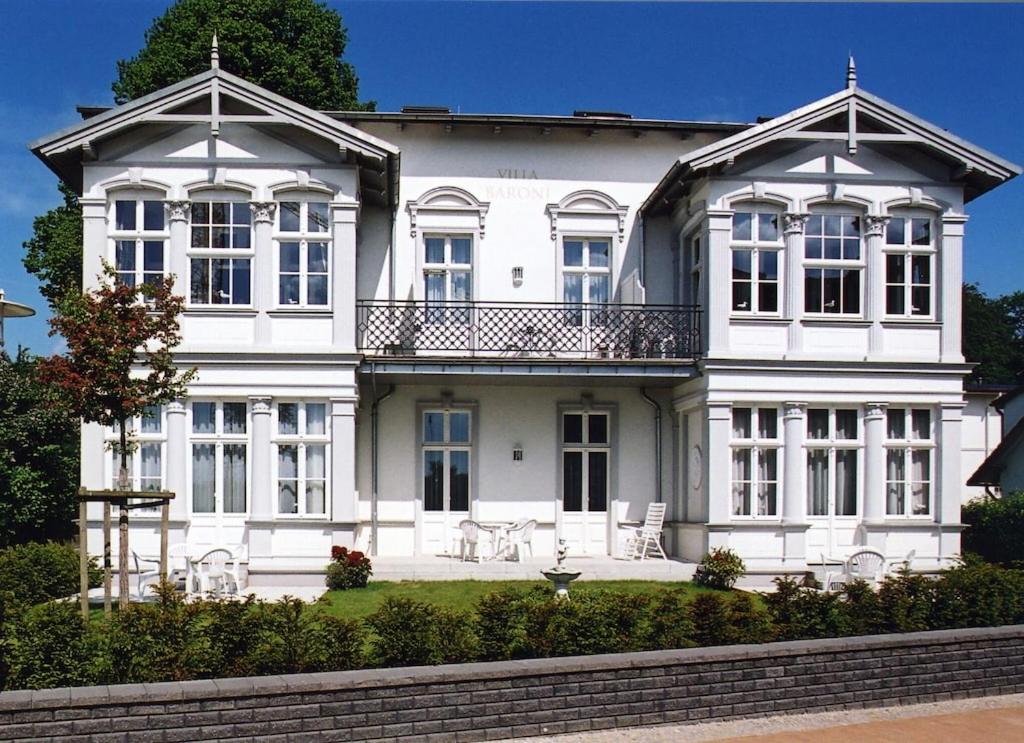 ein großes weißes Haus mit Balkon darüber in der Unterkunft Schöne Ferienwohnung in Seebad Bansin 200m vom Strand (Heringsdorf, Kaiserbäder, Usedom) in Bansin