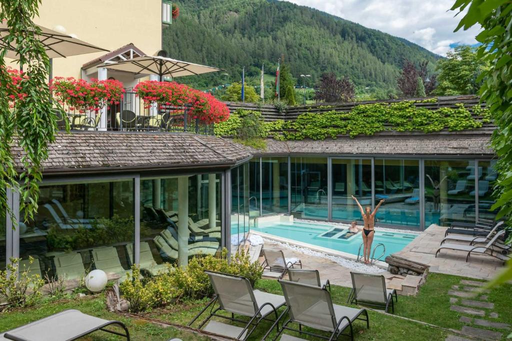 ディマーロにあるAlpholiday Dolomiti Wellness & Family Hotelの中庭にスイミングプールと椅子がある家